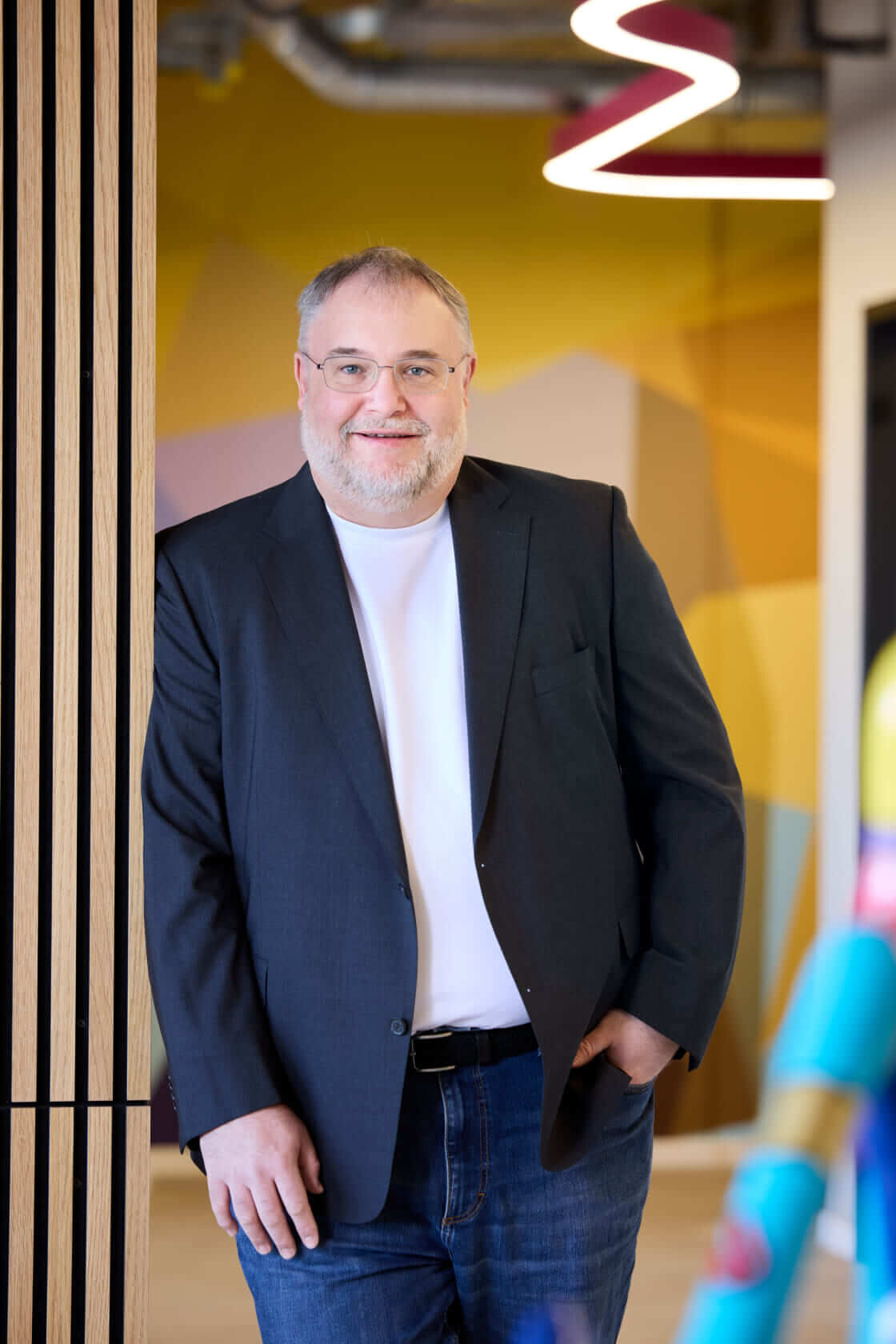 Björn Bröhl, CEO of Scompler, leans casually against a modern wall with wooden slats in the Munich office.