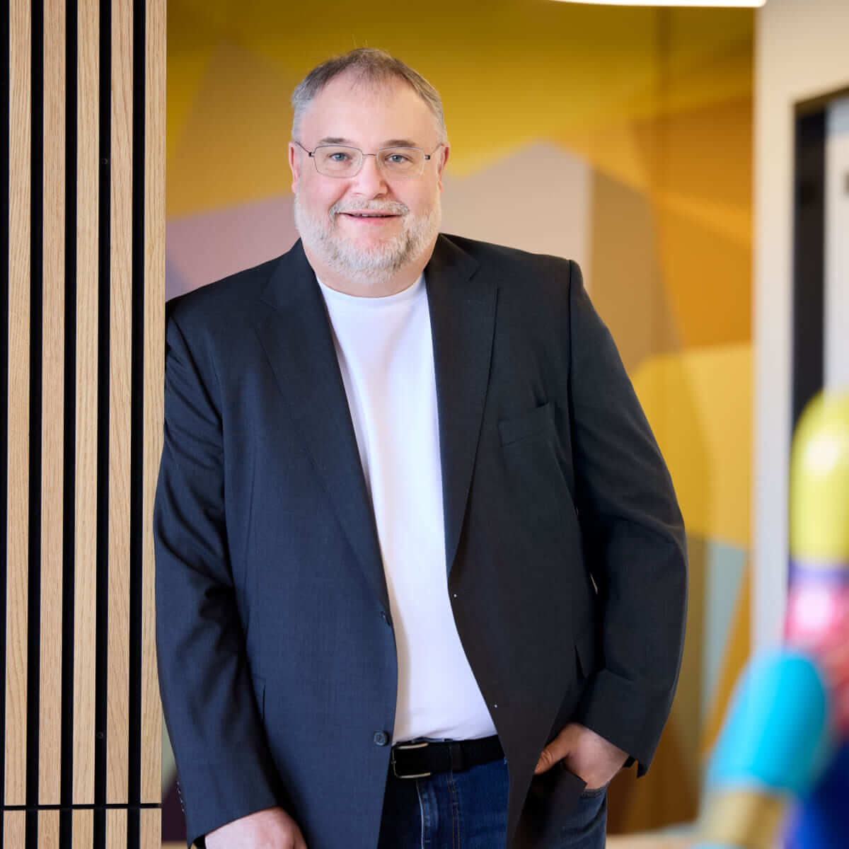 Björn Bröhl, CEO of Scompler, leans casually against a modern wall with wooden slats in the Munich office.
