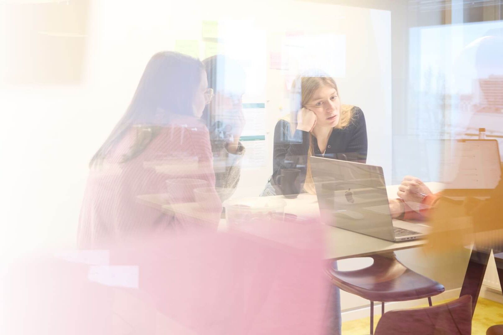 Kreatives Team im New Work-Büro, engagiert in effektiver interner Kommunikation am Laptop.