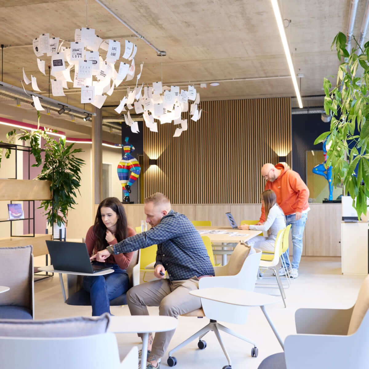 Modernes B&uuml;ro Arbeitsplatz f&ouml;rdert Team Zusammenarbeit; Mitarbeiter besprechen Ideen an Laptops in inspirierender Umgebung.