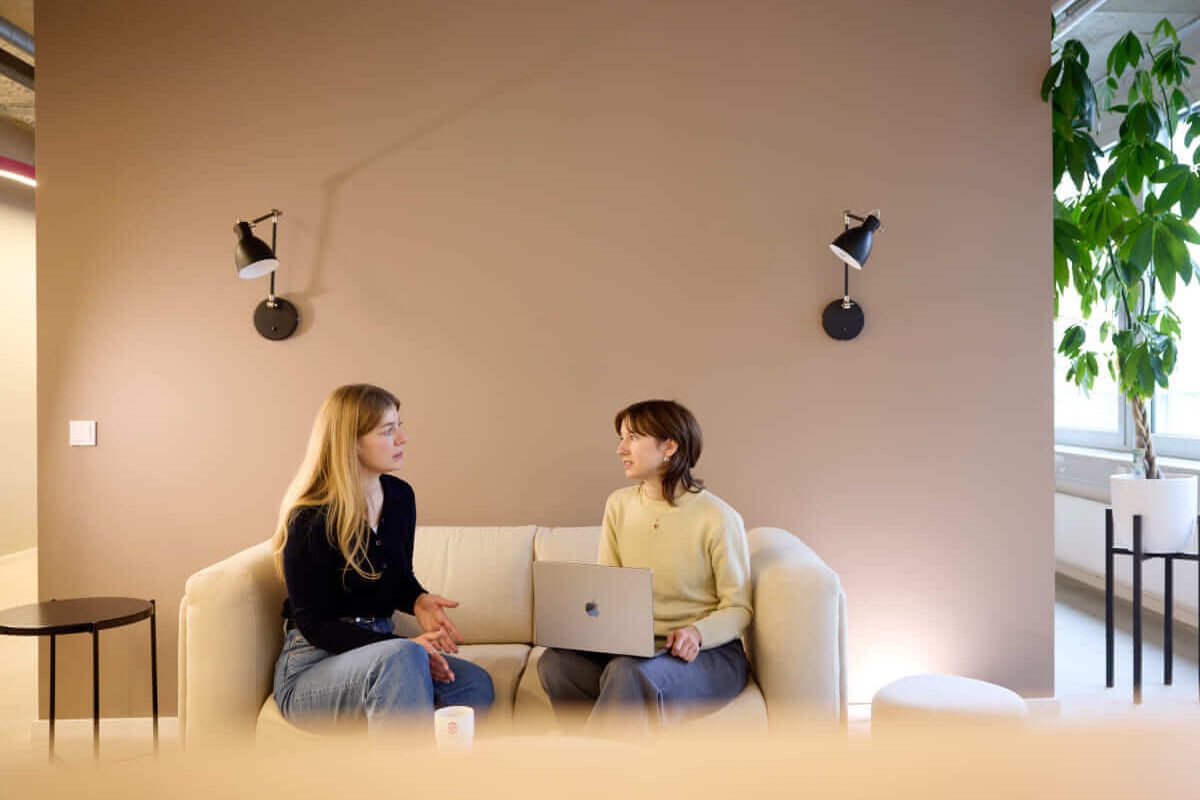 Kolleginnen im lebhaften Büro: Eine Besprechung auf dem Sofa im inspirierenden Co-Working Space.